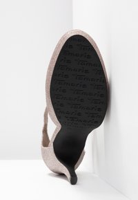 Talons de chaussure roses scintillants avec côtés ouverts, bout pointu et semelle en caoutchouc noire texturée ornée du logo de la marque.