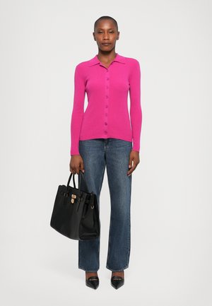 Fitted, ribbed pink cardigan with a collared neckline, long sleeves, and buttons. Paired with dark blue flared jeans and black handbag.