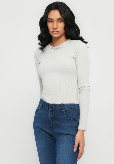 Lichtgrijze ribbelige lange mouw top gecombineerd met donkerblauwe slim-fit jeans met een knop en vijf zakken. Zachte textuur en getailleerd ontwerp.