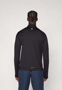 Fekete, hosszúujjú sportpóló, texturált anyagból, magas gallérral és egy kis logóval a nyak hátsó részén.