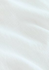 Tela de lino blanca con una superficie ligeramente texturizada, que muestra pliegues suaves y una apariencia ligera y aireada.