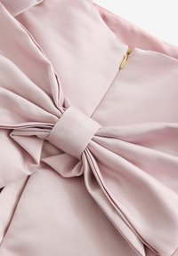 Tessuto di raso rosa chiaro con un dettaglio a fiocco attorcigliato, morbide pieghe e un'accenno in metallo dorato. Texture liscia con una leggera lucentezza.