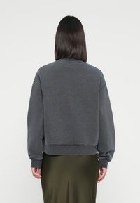 Gray sweatshirt with a cropped design, ribbed cuffs and hem, and a soft texture, paired with a smooth olive green skirt.
