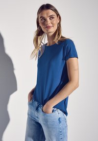 Blå kortärmad t-shirt i ett slätt material, med en klassisk rund halsringning. Kombinerad med ljusblå jeans, vilket ger en avslappnad stil.