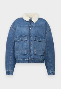 Jeansjacka i ljusblå färg med knappstängning, två framfickor på bröstet och en vit shearlingkrage. Avslappnad passform med synliga sömmar.