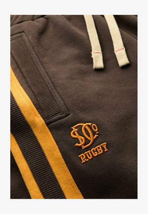 Felpa marrone con cordini beige, presenta un logo ricamato e la scritta "RUGBY" in arancione. Il lato ha strisce verticali gialle e una texture a coste.