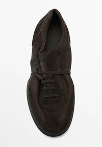 Scarpa in suede marrone scuro con punta rotonda, lacci piatta e cuciture a contrasto. Suola in gomma con dettaglio testurizzato sul tallone.