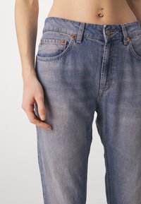 Vaqueros de mezclilla azul claro con un ajuste relajado, que cuentan con cinco bolsillos, detalles en cobre y un sutil desgaste para aportar textura.