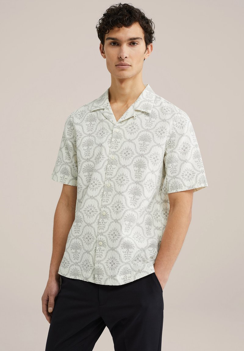 Cămașă cu mânecă scurtă dintr-un material verde deschis, cu un model floral. Design cu închidere prin nasturi și guler. Textură netedă și croială lejeră.