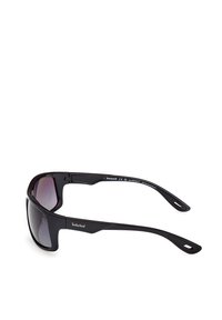 Černé plastové sluneční brýle s obepínajícím designem, gradientními čočkami a logem na straně. Vyznačují se pevným, hladkým povrchem.