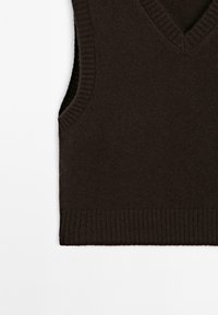 Brown knitted sleeveless sweater with a V-neck, featuring ribbed edges and a soft texture. Simple design with no patterns or accents.