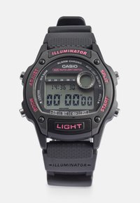 Relógio digital Casio com pulseira de borracha preta, apresentando um mostrador quadrado, detalhes em vermelho e vários botões para funções como alarme e luz.