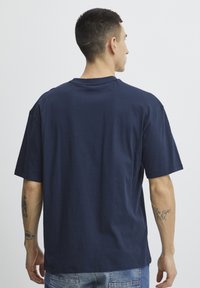 Navy blue cotton T-shirt with a relaxed fit, short sleeves, and a crew neckline, featuring a smooth texture and minimalistic design.