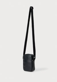 Bolsa de ombro em couro preto com forma retangular, textura suave, fecho de zipper e alça ajustável. Design minimalista sem hardware visível.