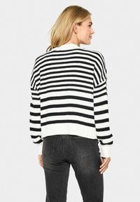 Pull en tricot rayé noir et blanc au design cropped avec un ourlet côtelé, doté de manches larges et d'un tissu texturé.