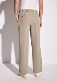 Lichtbeige wijde broek met een ontspannen tailleband, zijzakken en een gladde textuur, gezien vanaf de achterkant.