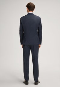 Granatowy garnitur o teksturowanym wykończeniu, z jednozapięciową marynarką i prostymi spodniami, prezentowany z tyłu.