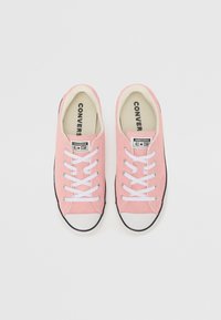 Růžové plátěné tenisky s bílými šňůrkami, gumovou podrážkou a černými detaily. Logo "Converse All Star" na jazyku. Hladký povrch po celém obvodu.