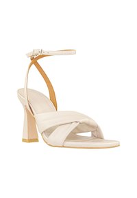 Sándal de tacón alto con tiras en cuero beige, con un diseño anudado en la parte delantera y un tacón cuadrado con una base texturizada.