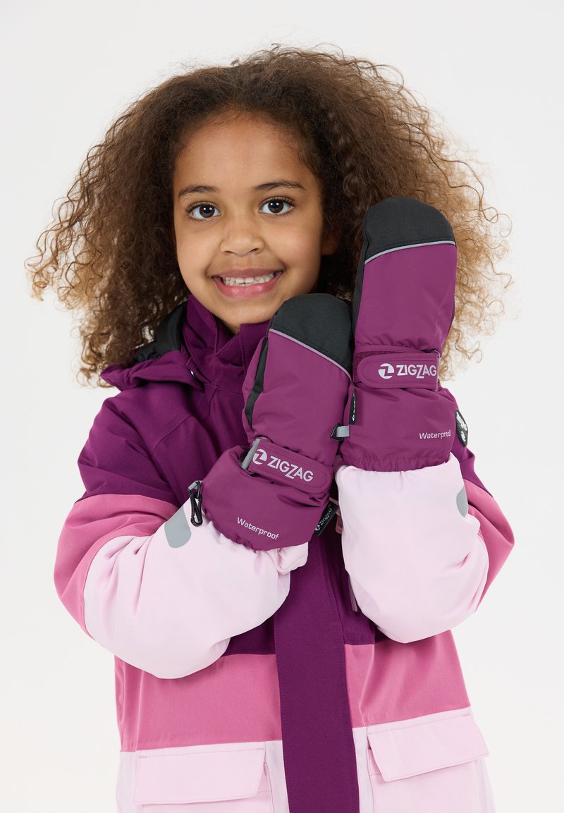 Moufle violette et noire avec des accents réfléchissants, étiquetée "ZIGZAG Waterproof", portées par un enfant dans une veste de ski rose avec des blocs de couleur.