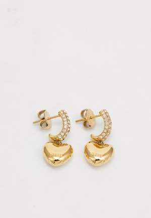 Gold-tone earrings with heart-shaped pendants and clear rhinestone accents. Each earring features a curved hoop design. Branding visible.