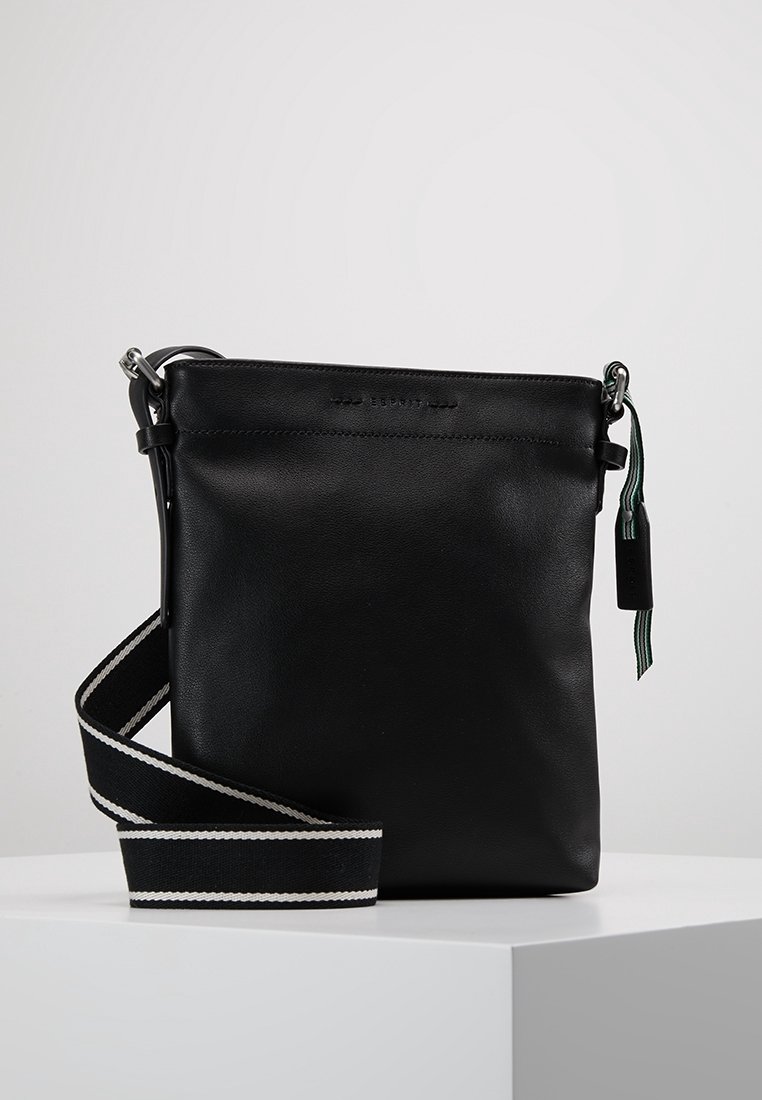 Czarna skórzana torba na ramię z regulowanym paskiem w paski, wyposażona w górne zamknięcie na suwak i małą ozdobną zawieszkę.