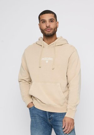 Beige hooded sweatshirt with front pocket, drawstring hood, and white logo text in the center. Cotton material, relaxed fit. Casual design.