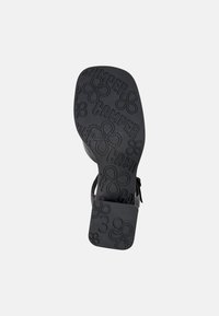 Black shoe sole featuring embossed "CAMER" logo and floral patterns, with a square heel and size "39" marked on the side.
