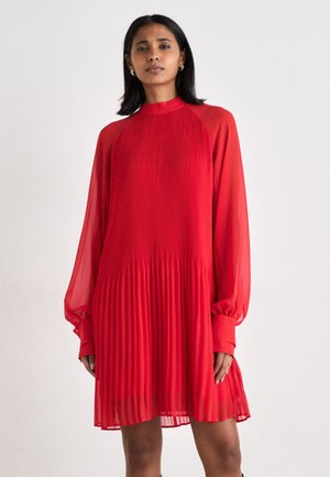 Rotes faltiges Kleid mit langen, durchsichtigen Ärmeln und hohem Kragen. Leichter Stoff sorgt für eine fließende Silhouette.