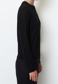 Zwarte gebreide trui met lange mouwen en een ronde halslijn. Heeft aansluitende mouwen en een rechte zoom. Gladde textuur, eenvoudig design, geen zichtbare patronen.