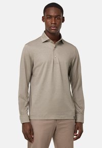 Khaki dlhý rukáv polo tričko vyrobené z mäkkej látky, s golierom a zapínaním na tri gombíky. Zdobené jemným logom pri leme.