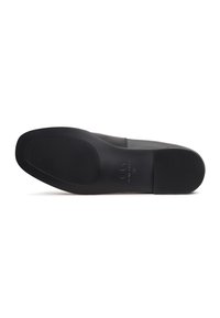 Black leather shoe sole featuring a textured rubber surface with a slight curve at the toe and embossed branding on the heel area.