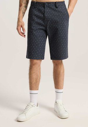 Granatowe szorty z tkaniny w rozproszony biały wzór w kropki, o prostym kroju, z bocznymi kieszeniami i zapięciem na guzik.