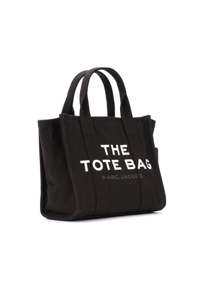 Čierna plátnená taška s dvoma rukoväťami, na prednej strane s bielym textom "THE TOTE BAG" a "MARC JACOBS". Čistý dizajn, obdĺžnikový tvar.