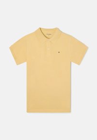 Camisa polo amarilla de tela suave, con un cuello clásico, tres botones y un pequeño logo en el lado izquierdo del pecho. Diseño de mangas cortas.