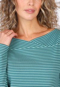 Tannengrünes gestreiftes Oberteil mit crossover-Ausschnitt und langen Ärmeln, gefertigt aus weichem Stoff mit abwechselnd hellen und dunklen Streifen.
