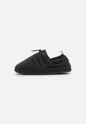 Chaussures à enfiler noires rembourrées avec une texture douce, bout arrondi, ouverture élastique et semelle plate. Design minimaliste avec des détails de couture subtils.