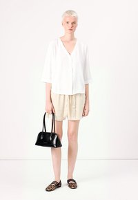 White v-neck blouse, loose beige shorts, black handbag, and leopard print flats. Simple design with light fabrics and neutral colors.