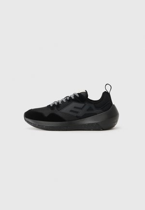 Sneaker de sport noir avec une tige en maille et en daim, des lacets texturés, un logo audacieux et une semelle en caoutchouc solide avec des accents mouchetés.