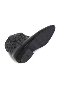 Black leather ankle boot with pyramid-shaped studs, a side buckle, and a textured sole. The heel is moderately chunky and sturdy.