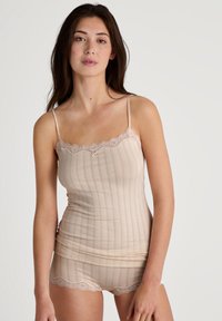 Completo canotta e pantaloni corti beige realizzato in materiale morbido, caratterizzato da righe verticali, bordo in pizzo al colletto e all'orlo, con spalline regolabili.