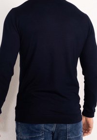 Granatowy sweter dziany z długimi rękawami i okrągłym dekoltem. Gładka faktura, dopasowany fason oraz ściągacz u dołu i na mankietach.