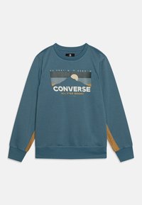 Teal long-sleeve sweatshirt with ribbed cuffs, tan elbow patches, and a mountain graphic with "CONVERSE ALL STAR BRAND" text on front.