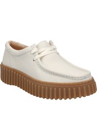 Scarpe di pelle bianca con punta arrotondata e una suola spessa e rigata di colore marrone. Design con lacci, con lacci e dettagli di cucitura di colore chiaro.