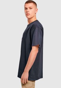 Marineblå bomulds t-shirt med løs pasform, korte ærmer og rund halsudskæring. Har et minimalistisk design uden synlige mønstre eller logoer.