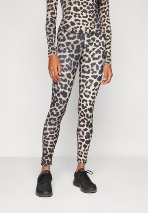 Leggings de estampado de leopardo con un patrón en beige y negro, hechos de un material suave y elástico. Combinados con zapatillas deportivas negras.