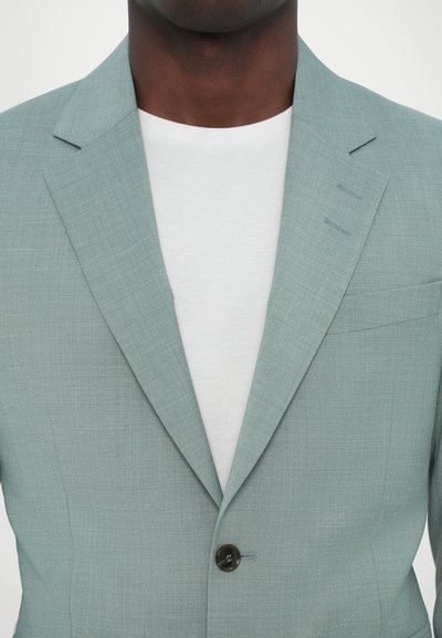 Hellgrüner, taillierter Blazer mit glatterTextur, Reverskragen und einem einzelnen Knopfverschluss. Trägt man über einem weißen Rundhalsausschnitt-T-Shirt.