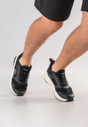 Zwarte sportschoenen met een bovenwerk van mesh, een witte middenzool en een zwarte rubberen buitenzool. Inclusief veters en een logo aan de zijkant.