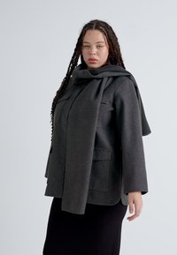 Dunkelgrauer Wollmantel mit Schalkragen, offener Vorderseite und zwei Fronttaschen. Das Design ist locker geschnitten mit langen Ärmeln.