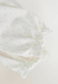 Witte stof met kleine beige stippen, voorzien van geplooide elastische manchetten. Zachte textuur, lichtgewicht ontwerp, geschikt voor warm weer.